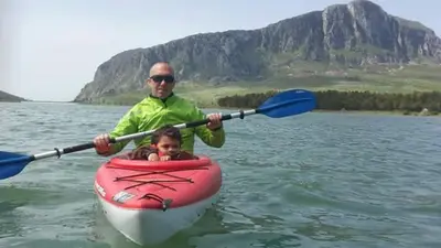 a man and a child in a kayak on the water at Flyhouse PARCHEGGIO AUTO BICI GRATUITO in Piana degli Albanesi