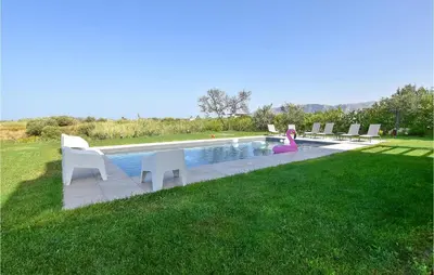 a pool with chairs and a little girl sitting next to it at 5 Bedroom Nice Home In Trappeto in Trappeto