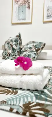 a pile of towels and a flower on a bed at Christian Guest House in Terrasini
