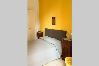 a bedroom with a white bed and a wooden nightstand at A casa di Enza B&B in Palermo