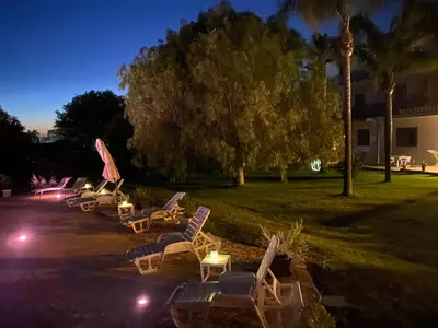 a row of lawn chairs and umbrellas at night at Villa Piruzzu CV Torre Mulinazzo app P in Cinisi