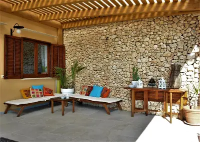 a patio with two benches and a stone wall at Casa Bouganville in Scopello