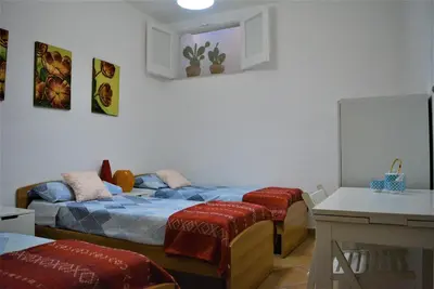 a bedroom with two beds and a table and a desk at Casa Bouganville in Scopello
