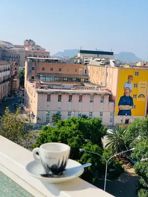 a cup of coffee sitting on a ledge with a city at Sostegno d'amore in Palermo