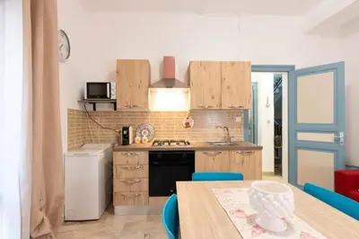 a kitchen with wooden cabinets and a table with blue chairs at Home holiday Kalanto in Castellammare del Golfo