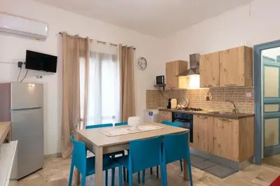 a kitchen with a table and some blue chairs at Home holiday Kalanto in Castellammare del Golfo