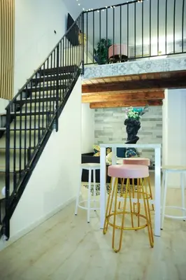 a dining room with a staircase and a table with stools at Casa vacanze Loft del Borgo in Palermo