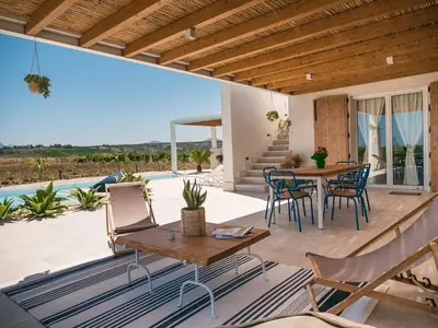 a patio with a table and chairs and a pool at VILLA DELLA QUBBAH with pool in Alcamo