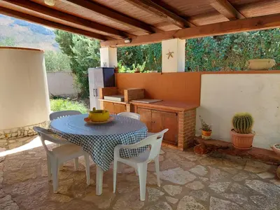 a patio with a table and chairs and a kitchen at Villa Maricetta in Castellammare del Golfo