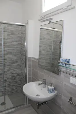 a bathroom with a sink and a shower with a mirror at Rahal B&B in Palermo