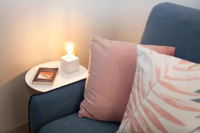 a candle on a table next to a blue chair with a pillow at NITI Palace in Castellammare del Golfo