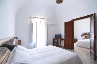a white bedroom with two beds and a window at Casa Azul in Terrasini