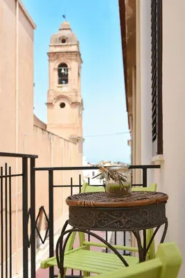 a table and chairs on a balcony with a clock tower at Casa Azul in Terrasini