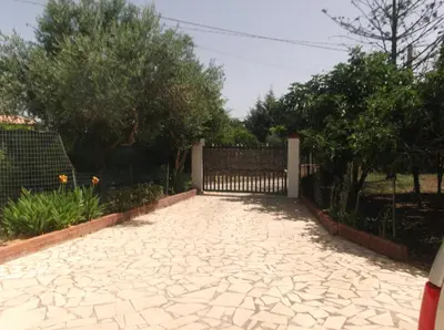 a stone driveway with a fence and trees at Villa Rosa in Castellammare del Golfo