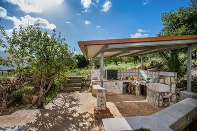 a patio with a stone grill with a roof at Villa Azuria con Piscina Privata Vista Mare in Scopello