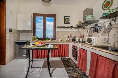 a kitchen with a counter with a table in it at Villa Azuria con Piscina Privata Vista Mare in Scopello