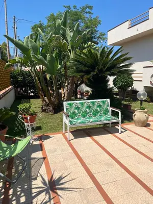 a green bench sitting on a patio in a yard at Trentuno Mondello Apartments in Mondello