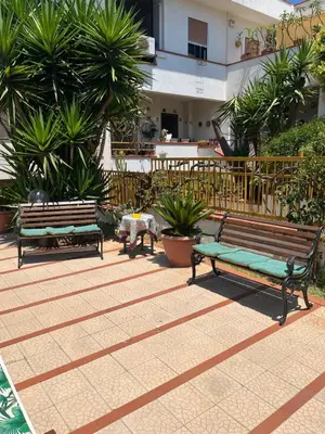 two benches sitting in a courtyard with palm trees at Trentuno Mondello Apartments in Mondello