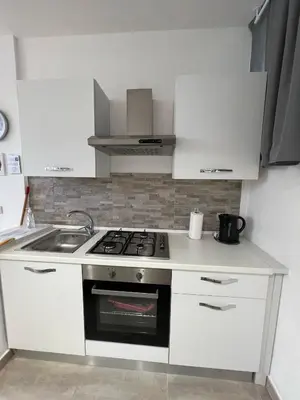 a white kitchen with a stove and a sink at Trentuno Mondello Apartments in Mondello