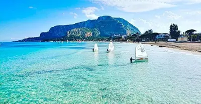 three small sailboats in the water on a beach at Trentuno Mondello Apartments in Mondello