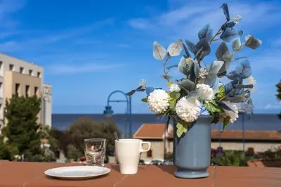 a blue vase with flowers on a table with a glass at La Casa di Martorana in Palermo