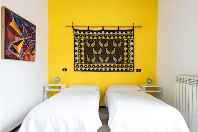 two beds in a room with a yellow wall at Iconic Apartment in Porta Carini by Wonderful Italy in Palermo
