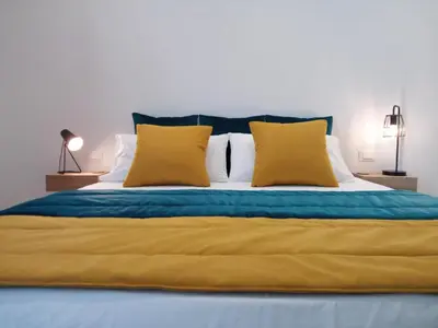 a large bed with yellow and blue sheets and pillows at Casa RALIVO di Sicilia in Balestrate