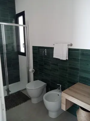 a green tiled bathroom with a toilet and a shower at Casa RALIVO di Sicilia in Balestrate