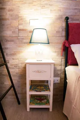 a white nightstand with a lamp on it next to a bed at DAI MORI in Palermo