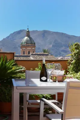 a white table with a bottle of wine and two chairs at A Casa Dell' Artista in Palermo