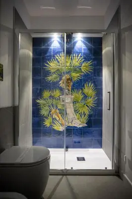 a bathroom with a toilet and a blue tiled wall at Acquarò Suite Apartments in San Vito lo Capo