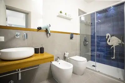 a bathroom with a sink and a toilet and a shower at Acquarò Suite Apartments in San Vito lo Capo