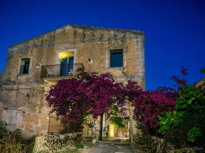 an old stone building with purple flowers on it at Baglio Colonna - Nature Noble Boutique in Partinico