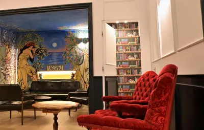 a living room with red chairs and a book shelf at Vespri Luxury Rooms & Suites in Palermo