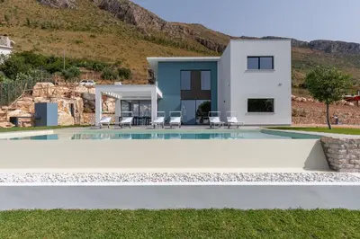a villa with a swimming pool in front of a house at Villa vista mare con piscina a sfioro a Scopello in Castellammare del Golfo