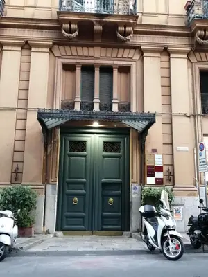 a scooter parked in front of a green door at suite ruggero settimo in Palermo