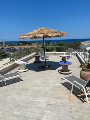 a patio with two tables and a straw umbrella at B&B Torre Pozzillo in Cinisi