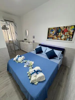 two beds in a bedroom with blue sheets and flowers at Casetta Blu Mondello zona Partanna in Palermo