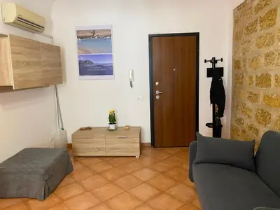 a living room with a couch and a cross on the wall at Casa arancio in Palermo