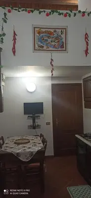a dining room with a table and a television on the wall at House Italia Holiday in Trabia