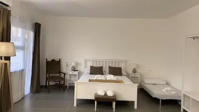 a white bedroom with a bed and a chair at Milu's Home in Palermo