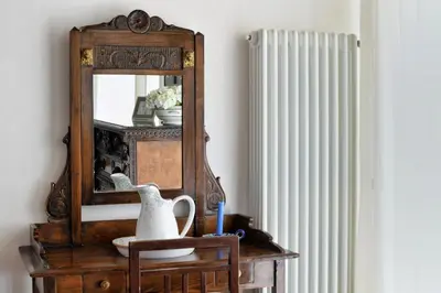 a mirror on a table with a vase and a chair at iFlat Palazzo Ragusi in Palermo