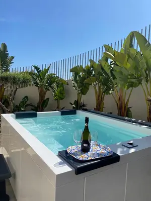 a table with a bottle of wine and glasses in a swimming pool at SOL Y MAR Camere e Appartamenti in Castellammare del Golfo