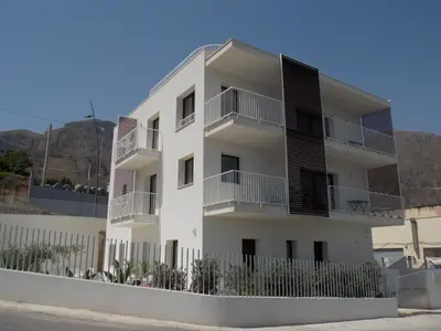 a white building with balconies and a fence at SOL Y MAR Camere e Appartamenti in Castellammare del Golfo
