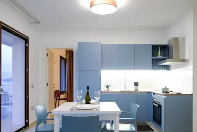 a kitchen with a white table and blue cabinets at SOL Y MAR Camere e Appartamenti in Castellammare del Golfo