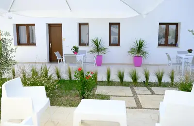 a patio with white chairs and tables and plants at SOL Y MAR Camere e Appartamenti in Castellammare del Golfo