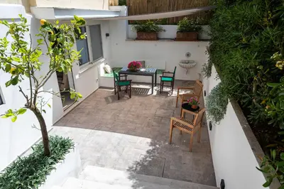 a patio with a table and chairs and a white wall at Casa Iole by DomuSicily in Mondello