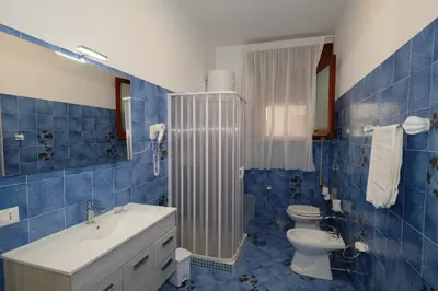 a blue tiled bathroom with a toilet and a sink at Villa Dolce Vita rooms in Castelluzzo