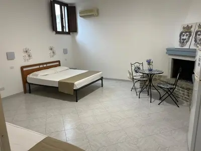 a bedroom with a bed and a table and a fireplace at Villa Dolce Vita rooms in Castelluzzo