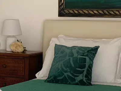 a green pillow sitting on a bed next to a nightstand at Villa Serendipity Terrasini in Terrasini
